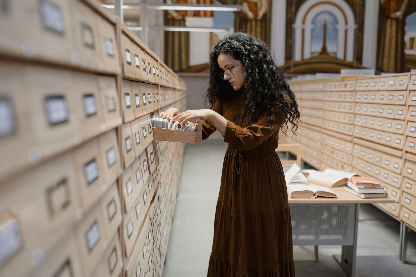 Frau durchsucht Karteikarten in einem historischen Bibliotheksarchiv