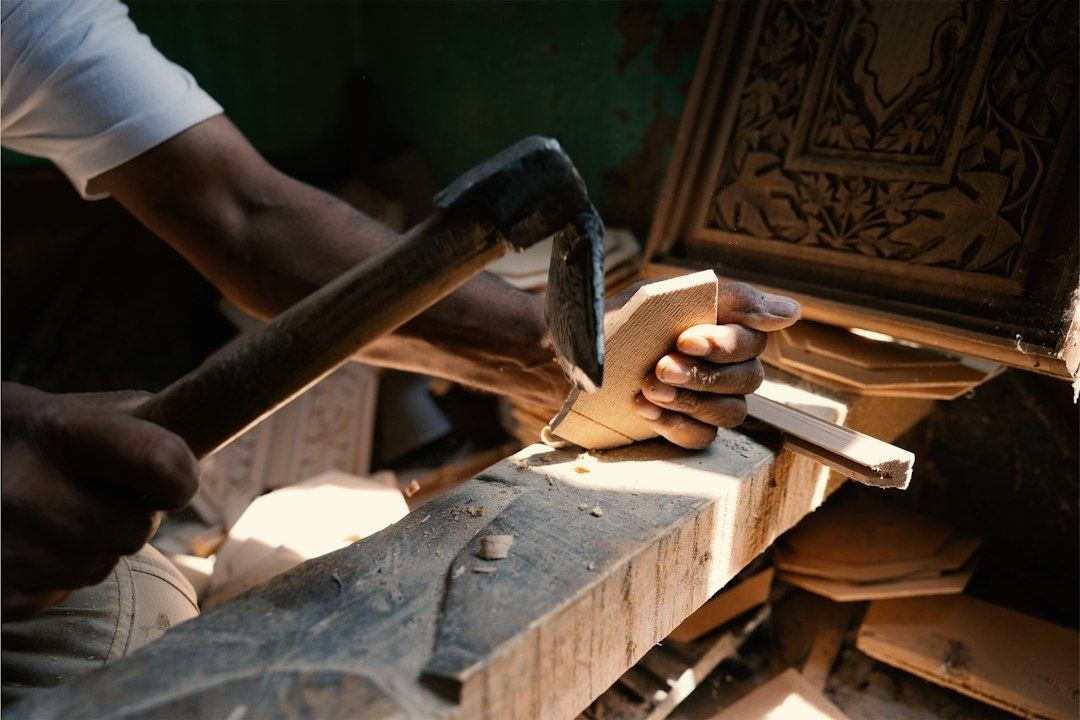 Handwerker bearbeitet ein Holzstück mit einem Hammer in einer Werkstatt